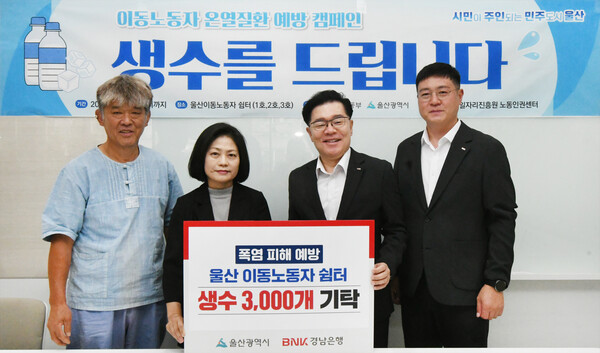 BNK경남은행 김기범 상무(오른쪽 두번째)가 10일 울산 이동노동자 쉼터(울산시 남구 달동 소재)를 방문해 울산경제일자리진흥원 박가령 전문위원에게 생수 기탁 증서를 전달하고 있다./BNK경남은행.